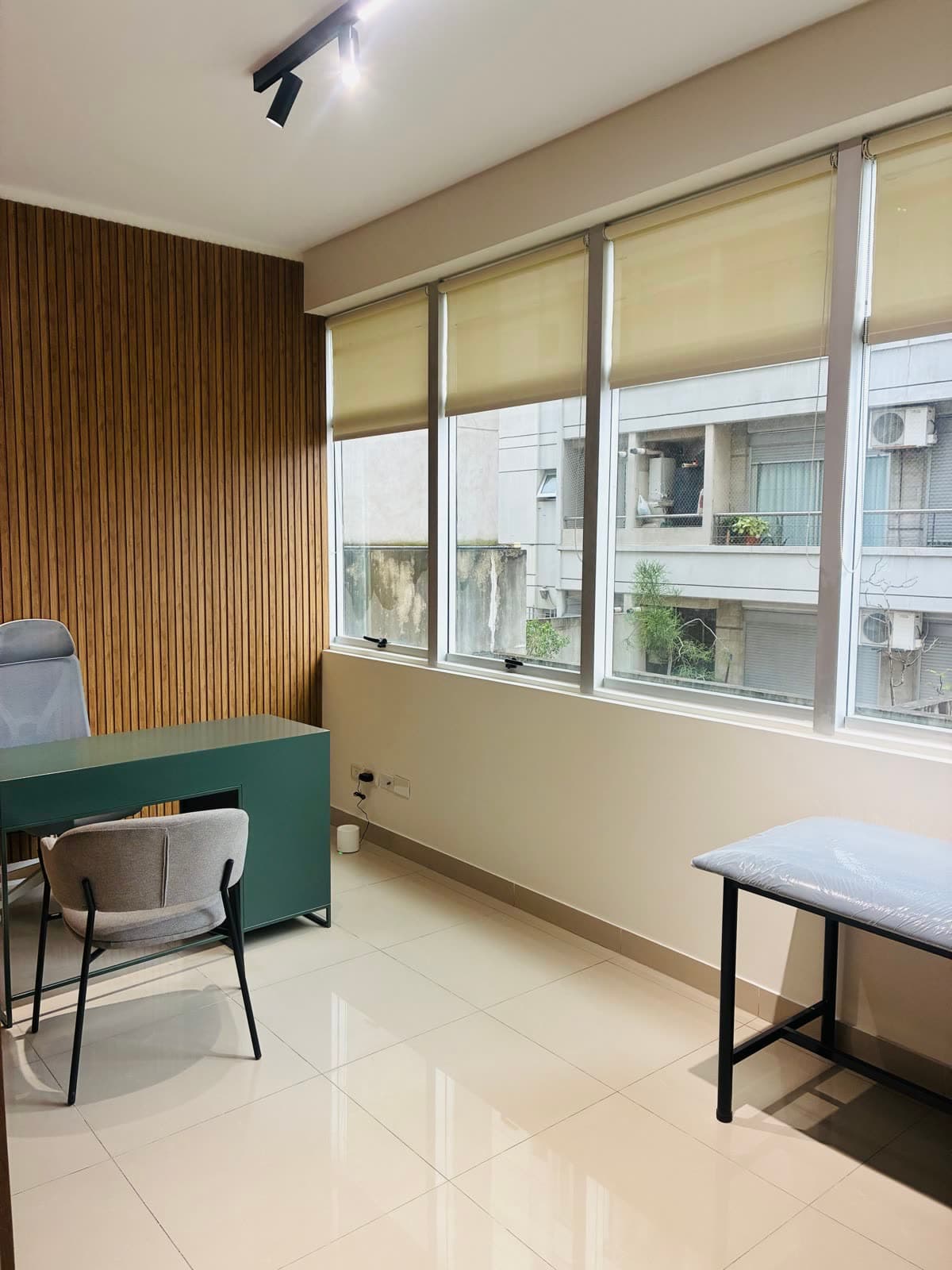 Consultorio 2 en Av. Córdoba 5779: escritorio verde, sillas y ventanal con cortinas