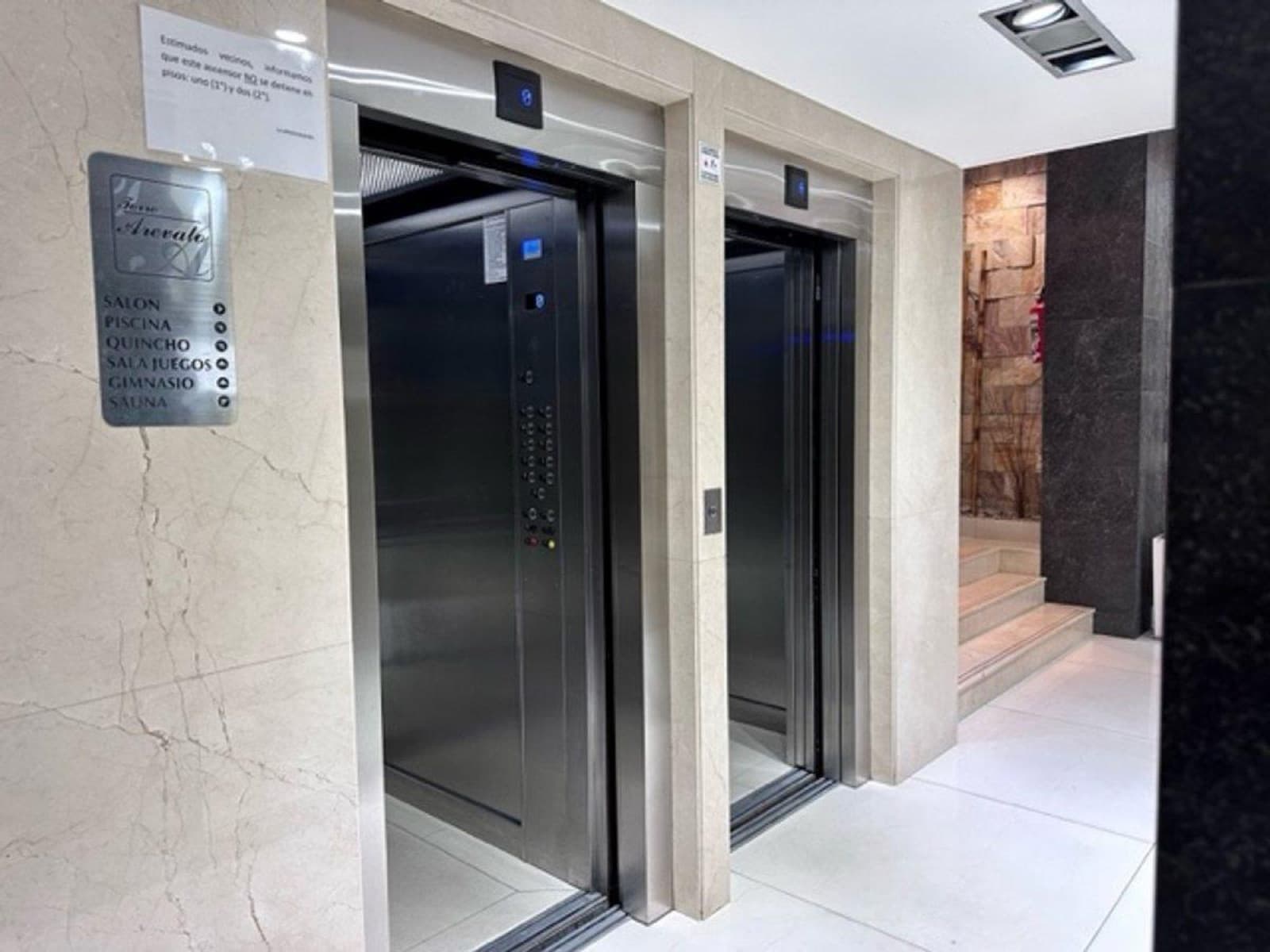 Hall de ascensores del edificio, con revestimiento en piedra e iluminación de autor